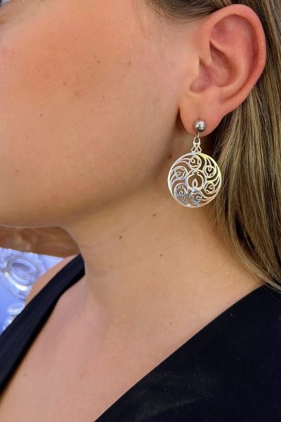 pendientes rosetón granada plateados colgando de la oreja, diseño intrincado. joyeria-plata-granada